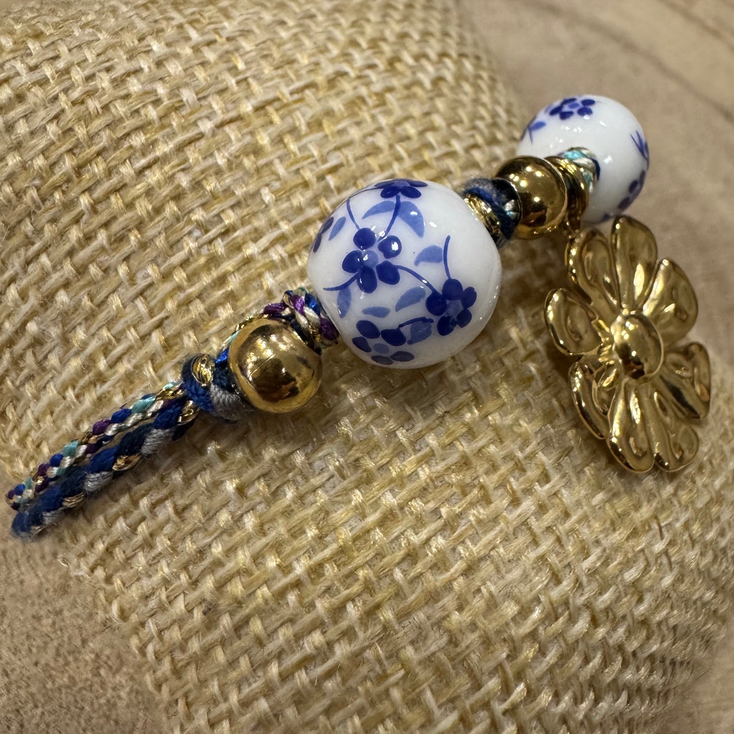 Pulseira Corda com Bolas de Flores Azuis e Brancas e Flor de Inox Dourado